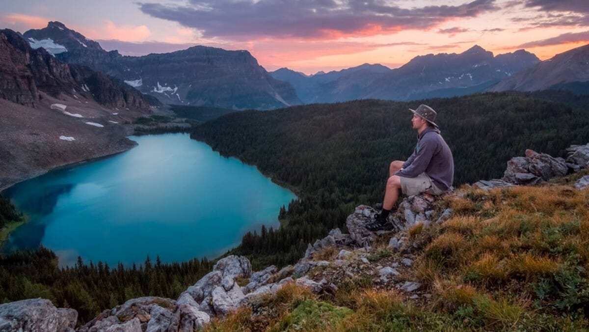 solitary man overlooking mountain lake