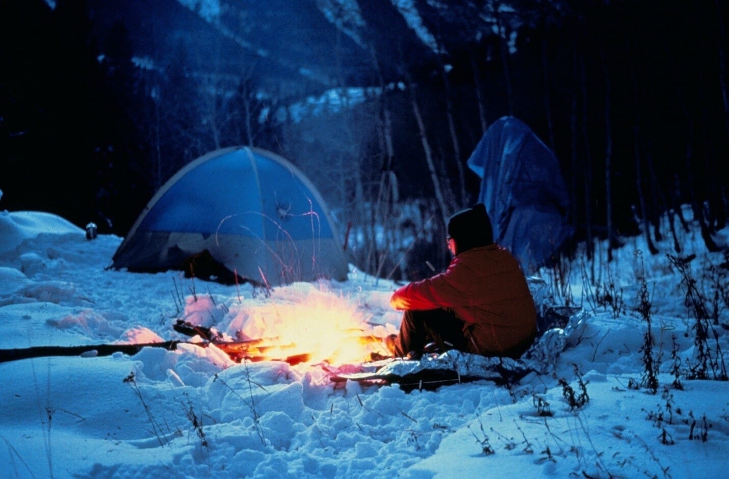 Winter camping with man in front of fire